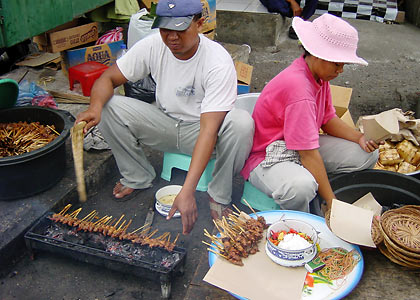 couple selling <i />sate ayam on a sidewalk in Jakarta